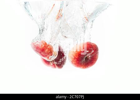 Mazzo di pesche di ciambelle isolate su bianco, spruzzando in acqua. Foto Stock