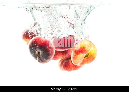 Mazzo di pesche di ciambelle isolate su bianco, spruzzando in acqua. Foto Stock