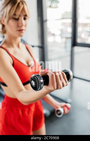 fuoco selettivo di donna sportiva che lavora fuori con i manubri nel centro sportivo Foto Stock