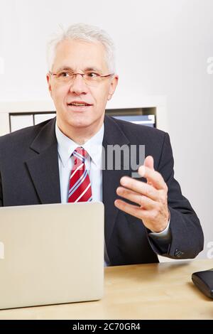 Uomo d'affari che usa il computer portatile alla scrivania fa una proposta Foto Stock