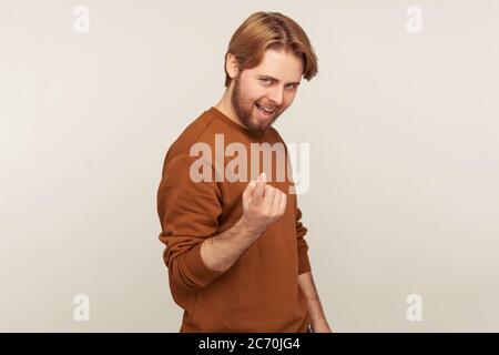 Vieni qui a me! Ritratto di uomo con la bearded positiva in felpa che si alza invitante in piedi con il gesto del dito beckoning, che guarda girando giocoso. indo Foto Stock