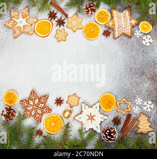 Biscotti allo zenzero natalizio in forma di fiocchi di neve, arancio secco, anice stellato e coni di abete su fondo di pietra grigia. Vista dall'alto. Simboli di Capodanno e C. Foto Stock