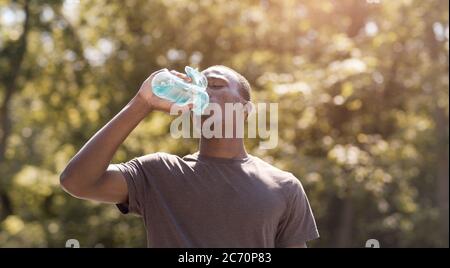 Uomo nero che beve acqua, che soffre di tempo caldo Foto Stock