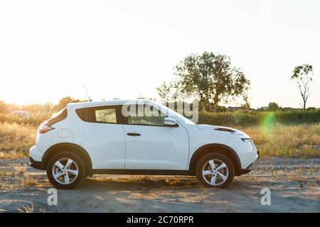 Novoselivka, regione di Dnipropetrovsk, Ucraina - 02 luglio 2020: Nissan Juke 2019 colore bianco vicino alla strada rurale al tramonto Foto Stock