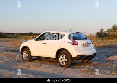 Novoselivka, regione di Dnipropetrovsk, Ucraina - 02 luglio 2020: Nissan Juke 2019 colore bianco vicino alla strada rurale al tramonto Foto Stock