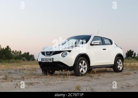 Novoselivka, regione di Dnipropetrovsk, Ucraina - 02 luglio 2020: Nissan Juke 2019 colore bianco vicino alla strada rurale al crepuscolo Foto Stock