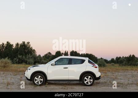 Novoselivka, regione di Dnipropetrovsk, Ucraina - 02 luglio 2020: Nissan Juke 2019 colore bianco vicino alla strada rurale al crepuscolo Foto Stock