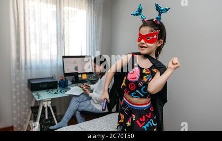 Ragazza che danzano in travestimento mentre la madre telelavoro Foto Stock