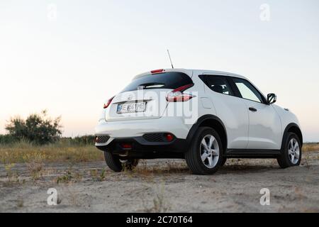 Novoselivka, regione di Dnipropetrovsk, Ucraina - 02 luglio 2020: Nissan Juke 2019 colore bianco vicino alla strada rurale al crepuscolo Foto Stock