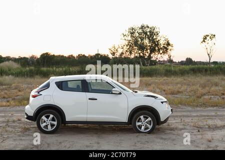 Novoselivka, regione di Dnipropetrovsk, Ucraina - 02 luglio 2020: Nissan Juke 2019 colore bianco vicino alla strada rurale al crepuscolo Foto Stock