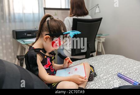 Ragazza che si disguisa mentre la madre telelavoro Foto Stock