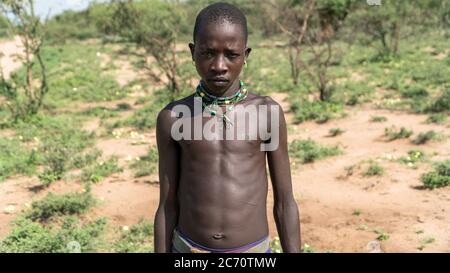 Omo, Etiopia - Settembre 2017: Ritratto di un ragazzo tribale etiope non identificato in piedi in campo aperto Foto Stock