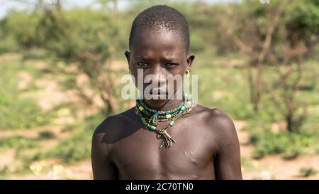 Omo, Etiopia - Settembre 2017: Ritratto di un ragazzo tribale etiope non identificato in piedi in campo aperto Foto Stock