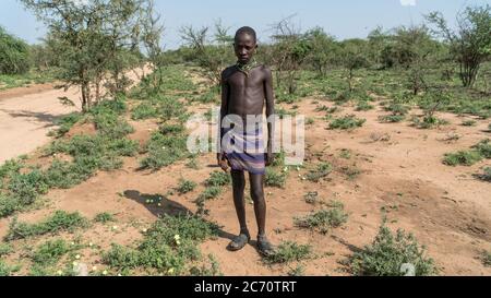 Omo, Etiopia - Settembre 2017: Ritratto di un ragazzo tribale etiope non identificato in piedi in campo aperto Foto Stock