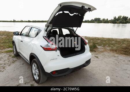 Novoselivka, regione di Dnipropetrovsk, Ucraina - 10 luglio 2020: Nissan Juke 2019 colore bianco vicino al fiume. Aprire il vano bagagli Foto Stock