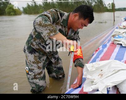 (200713) -- NANCHANG, 13 luglio 2020 (Xinhua) -- Hong Mianxue misura il livello dell'acqua fuori dalla diga nell'isolotto di Jiangxinzhou della città di Jiujiang, nella provincia di Jiangxi della Cina orientale, 12 luglio 2020. Hong Mianxue, 45 anni, è segretario del ramo del villaggio di Liuzhou del Partito Comunista Cinese. Nella lotta contro l'alluvione di quest'anno, è responsabile della pattugliatura e della protezione di una sezione dell'argine dell'isolotto di Jiangxinzhou. Dal 3 luglio, gli abitanti di Hong e dei villaggi sono stati attaccati al loro giorno e notte post per proteggere l'argine e l'isolotto. (Xinhua/Peng Zhaozhi) Foto Stock