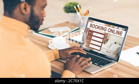 Black man prenotazione online di hotel, utilizzando un computer portatile Foto Stock