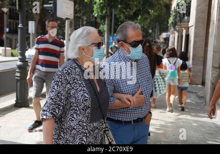 Palma, Spagna. 13 luglio 2020. Un uomo anziano e una donna anziana con guardie del bocca stanno camminando nel centro di Palma. A Maiorca e nelle altre isole Baleari, lunedì entrerà in vigore un'ampia gamma di maschere obbligatorie a causa della pandemia di Corona. Credit: Clara Margais/dpa/Alamy Live News Foto Stock