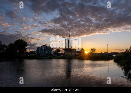 Sundown con il mulino a vento olandese nelle acque di Kralingse Plas, Rotterdam Foto Stock