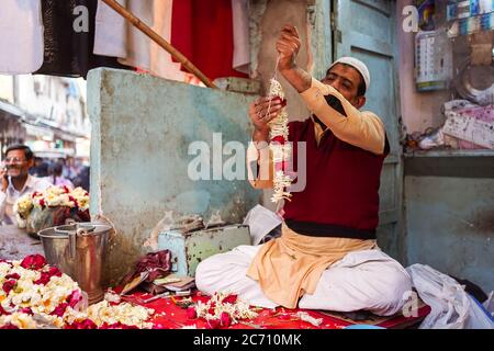 Nuova Delhi / India - 18 febbraio 2020: Uomo musulmano che prepara la corona tradizionale dei fiori a mano in negozio per strada di Old Delhi Foto Stock