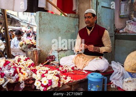 Nuova Delhi / India - 18 febbraio 2020: Uomo musulmano che prepara la corona tradizionale dei fiori a mano in negozio per strada di Old Delhi Foto Stock