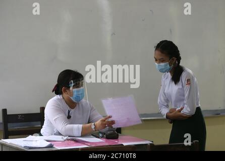 Yangon, Myanmar. 13 luglio 2020. Un insegnante spiega le regole della scuola per prevenire il virus COVID-19 ad uno studente il giorno di iscrizione scolastica a Yangon, Myanmar, 13 luglio 2020. Il Myanmar da martedì ha dato il via alle iscrizioni scolastiche per l'anno accademico 2020-2021, che è stato ritardato dovuto la pandemia di COVID-19. Credit: U Aung/Xinhua/Alamy Live News Foto Stock