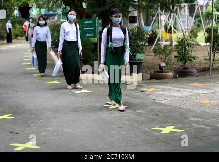 Yangon, Myanmar. 13 luglio 2020. Gli studenti che indossano schermi e maschere camminano in distanza sociale in una scuola durante la giornata di iscrizione scolastica a Yangon, Myanmar, 13 luglio 2020. Il Myanmar da martedì ha dato il via alle iscrizioni scolastiche per l'anno accademico 2020-2021, che è stato ritardato dovuto la pandemia di COVID-19. Credit: U Aung/Xinhua/Alamy Live News Foto Stock