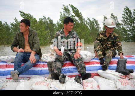 (200713) -- NANCHANG, 13 luglio 2020 (Xinhua) -- Hong Mianxue (C) e gli abitanti del villaggio riposano sulla diga nell'isolotto di Jiangxinzhou della città di Jiujiang, nella provincia di Jiangxi della Cina orientale, 12 luglio 2020. Hong Mianxue, 45 anni, è segretario del ramo del villaggio di Liuzhou del Partito Comunista Cinese. Nella lotta contro l'alluvione di quest'anno, è responsabile della pattugliatura e della protezione di una sezione dell'argine dell'isolotto di Jiangxinzhou. Dal 3 luglio, gli abitanti di Hong e dei villaggi sono stati attaccati ai loro posti giorno e notte per proteggere l'argine e l'isolotto. (Xinhua/Peng Zhaozhi) Foto Stock