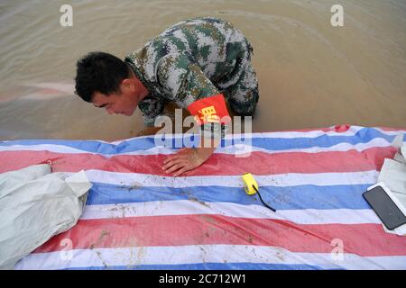 (200713) -- NANCHANG, 13 luglio 2020 (Xinhua) -- Hong Mianxue controlla il fondo della diga nell'isolotto di Jiangxinzhou della città di Jiujiang, provincia di Jiangxi della Cina orientale, 12 luglio 2020. Hong Mianxue, 45 anni, è segretario del ramo del villaggio di Liuzhou del Partito Comunista Cinese. Nella lotta contro l'alluvione di quest'anno, è responsabile della pattugliatura e della protezione di una sezione dell'argine dell'isolotto di Jiangxinzhou. Dal 3 luglio, gli abitanti di Hong e dei villaggi sono stati attaccati ai loro posti giorno e notte per proteggere l'argine e l'isolotto. (Xinhua/Peng Zhaozhi) Foto Stock