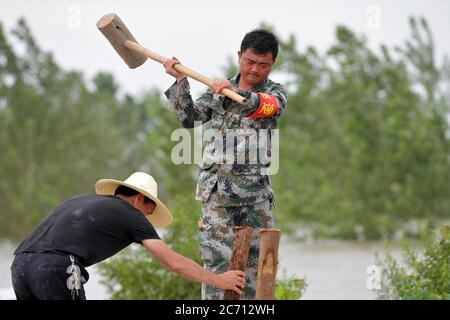 (200713) -- NANCHANG, 13 luglio 2020 (Xinhua) -- Hong Mianxue e un abitante del villaggio rinforzano la diga nell'isolotto di Jiangxinzhou della città di Jiujiang, provincia di Jiangxi della Cina orientale, 12 luglio 2020. Hong Mianxue, 45 anni, è segretario del ramo del villaggio di Liuzhou del Partito Comunista Cinese. Nella lotta contro l'alluvione di quest'anno, è responsabile della pattugliatura e della protezione di una sezione dell'argine dell'isolotto di Jiangxinzhou. Dal 3 luglio, gli abitanti di Hong e dei villaggi sono stati attaccati ai loro posti giorno e notte per proteggere l'argine e l'isolotto. (Xinhua/Peng Zhaozhi) Foto Stock