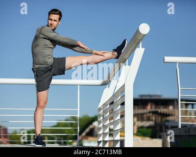 Attività sportive. Corridore atletico che fa esercizio di stretching, preparandosi per l'allenamento Foto Stock