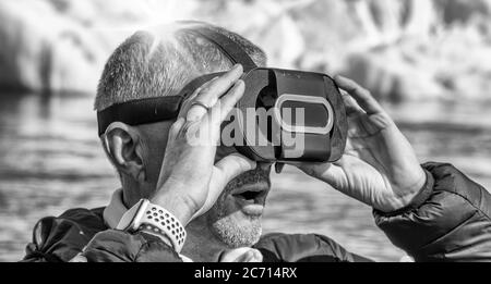 Uomo stupefatto che indossa occhiali VR con iceberg che galleggiano nella laguna di Jokulsarlon, Islanda. Foto Stock