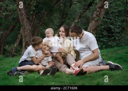 Picnic per famiglie all'aperto. Mamma papà e tre bambini trascorrono insieme del tempo di qualità. Foto Stock
