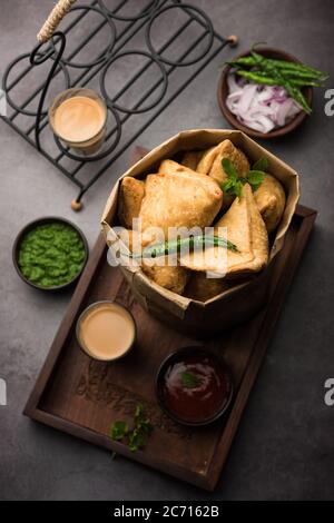 Samosa - pasticceria fritta/cotta a forma triangolare con ripieno di salato, popolari spuntini Indian Tea Time, serviti con chutney verde, ketchup di pomodoro Foto Stock