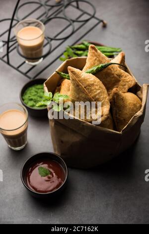 Samosa - pasticceria fritta/cotta a forma triangolare con ripieno di salato, popolari spuntini Indian Tea Time, serviti con chutney verde, ketchup di pomodoro Foto Stock