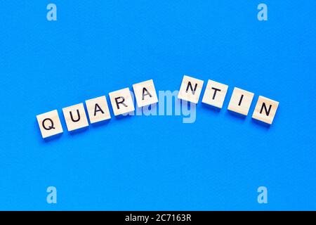 La parola interrotta quarantena. La fine della quarantena. La parola quarantena terminava su sfondo blu in lettere di legno. Foto Stock