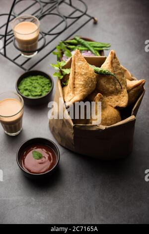 Samosa - pasticceria fritta/cotta a forma triangolare con ripieno di salato, popolari spuntini Indian Tea Time, serviti con chutney verde, ketchup di pomodoro Foto Stock