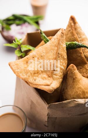 Samosa - pasticceria fritta/cotta a forma triangolare con ripieno di salato, popolari spuntini Indian Tea Time, serviti con chutney verde, ketchup di pomodoro Foto Stock