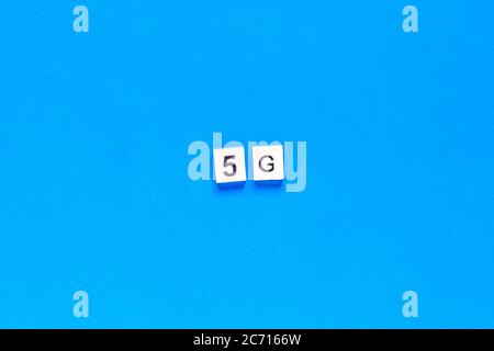 5 G. cinque G, scritte in lettere di legno su sfondo blu. Layout piatto. Rete wireless. Nuova tecnologia. Vista dall'alto. Foto Stock
