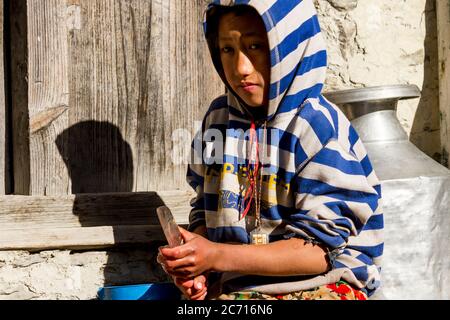 Jhong, Nepal - 8 novembre 2015: Ragazzo nepalese tagliando patate vicino a casa sua. Foto Stock