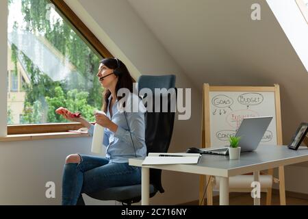 Donne lavano le finestre mentre su una chiamata di conferenza al lavoro. Nuovo concetto normale. Foto Stock