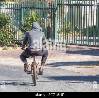 Alberton, Sudafrica - i giovani neri non identificati cavalcano una piccola bicicletta in un'immagine pubblica di strada in formato paesaggio Foto Stock