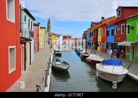 Burano, Venezia, Veneto, Italia. Vista su uno dei canali dell'isola e sullo sfondo il campanile pendente della chiesa di San Martino. Foto Stock