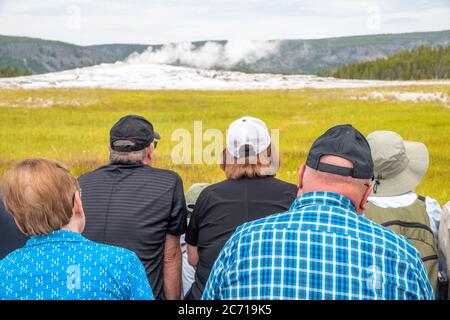 Vista posteriore dei turisti in attesa di eruzione del geyser Old Faithful, Parco Nazionale di Yellowstone. Foto Stock