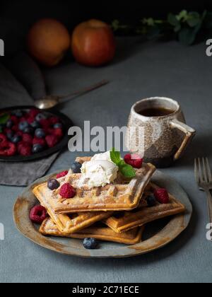 Waffle belgi con lamponi, sciroppo di cioccolato. Colazione con tè su sfondo scuro Foto Stock