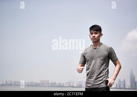 giovane adulto asiatico pronto a correre all'aperto in riva al mare Foto Stock
