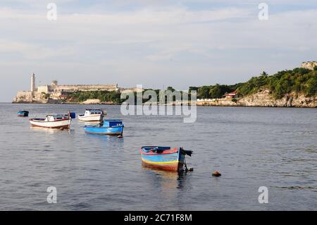 Vista su una barca da pesca rustica alla baia di l'avana al tramonto, faro di morro all'Avana Foto Stock