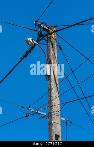 Vecchio telefono, cablaggio elettrico e luce stradale su palo telegrafico nella Francia rurale. Foto Stock