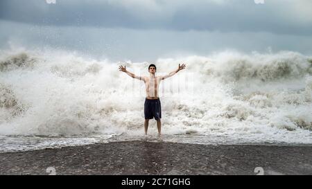 Antalya - Turchia - 17 ottobre 2013: Giovane uomo in piedi contro le onde del mare con spruzzi in un clima torbido Foto Stock