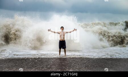 Antalya - Turchia - 17 ottobre 2013: Giovane uomo in piedi contro le onde del mare con spruzzi in un clima torbido Foto Stock